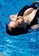 A woman in a black bathing suit floating in a pool.