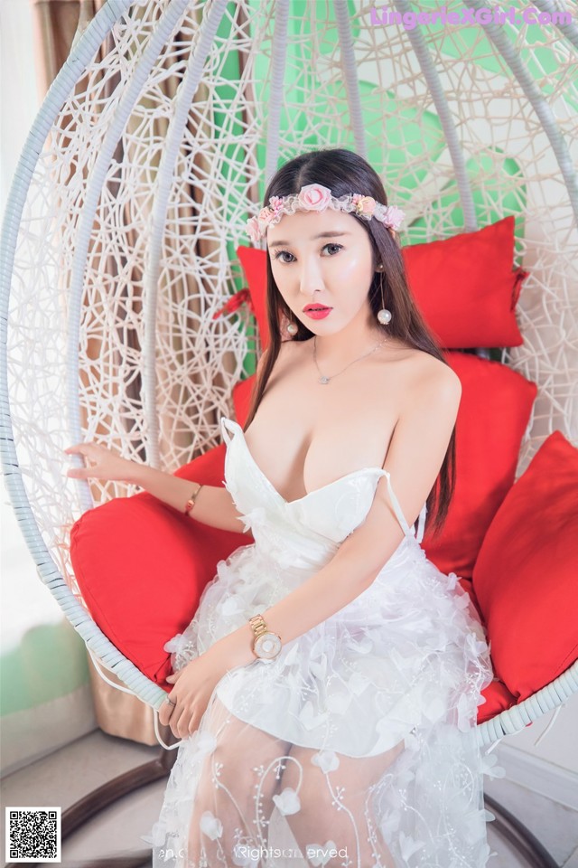 A woman in a white dress sitting on a red chair.