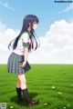 A girl in a school uniform standing in a field of grass.