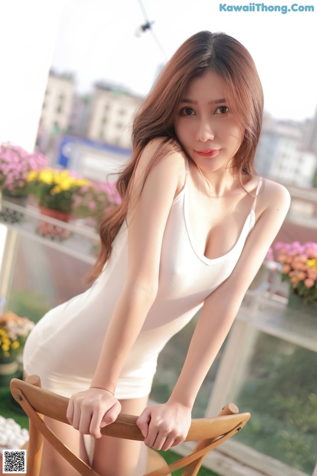 A woman in a white dress posing on a balcony.