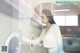 A woman standing in front of a washing machine.