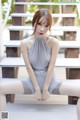 A woman in a gray dress sitting on some steps.