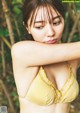 A woman in a yellow bikini posing for a picture.