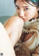 A woman sitting on top of a bed next to a pillow.