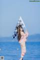 A woman in a bikini holding a flag on the beach.