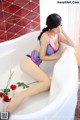 A woman sitting in a bathtub with a rose in her hand.