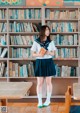 A woman standing in front of a bookshelf holding a book.