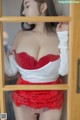 A woman in a red lingerie looking out of a window.