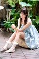 A woman in a blue dress sitting on a wooden floor.