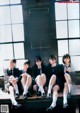 A group of young women sitting on top of a wooden bench.