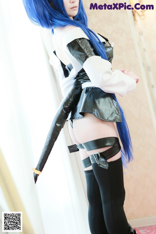 A woman with long blue hair is posing for a picture.