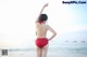 A woman in a red bikini standing on the beach.