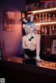 A woman in bunny ears sitting at a bar.