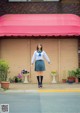 A woman in a school uniform standing in front of a building.