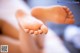 A close up of a person's bare feet on a bed.