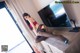 A woman sitting on top of a dresser next to a television.