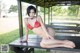 A woman in a red bikini sitting on a picnic table.