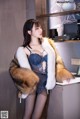 A woman in lingerie and fur coat posing for a picture.