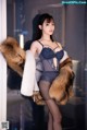 A woman in lingerie and fur coat posing for a picture.