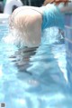 A woman in a blue dress is swimming in a pool.