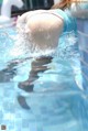 A woman in a blue bikini is swimming in a pool.