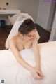 A woman in a wedding dress laying on a bed.