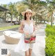 A woman in a white dress and straw hat holding a straw bag.