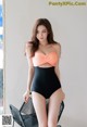 A woman in a black and orange one piece swimsuit posing for a picture.