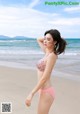 A woman in a pink bikini standing on a beach.