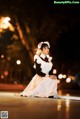 A woman in a white dress sitting on the ground.