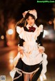 A woman dressed in a maid outfit is walking down the street.