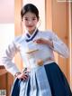 A woman in a blue and white hanbok poses for a picture.