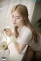 A woman sitting on a window sill next to a vase of flowers.