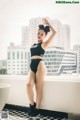 A woman in a black bikini posing on a balcony.