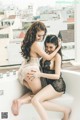 A couple of women sitting on top of a bathtub.