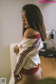 A woman in a white jacket and red panties sitting on a desk.