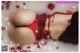 A woman in a red lingerie laying in a bathtub with rose petals.