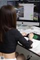 A woman sitting at a desk using a computer.