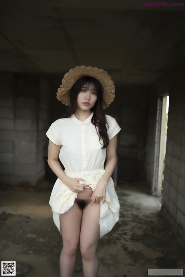 A woman in a white shirt and a straw hat posing for a picture.