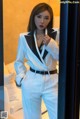 A woman in a white suit standing in front of a mirror.