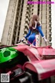 A woman in a blue and red outfit standing on top of a red and green vehicle.