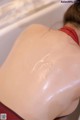 A woman in a bathtub with a lot of oil on her back.