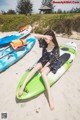 A woman sitting on top of a green and blue kayak.