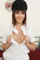 A woman in a white shirt and black hat posing on a bed.