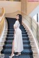 A woman in a white dress standing on a set of stairs.