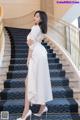 A woman in a white dress standing on a set of stairs.