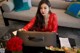 A woman in a red dress sitting at a table with a purse.